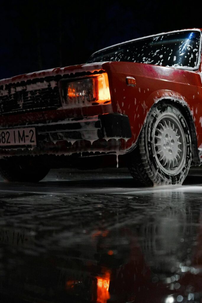 a red car covered in soap from improper rinsing in automatic carwash