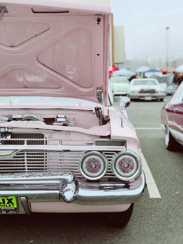 pink classic car with the hood lifted, showing off mechanical restoration and paint correction